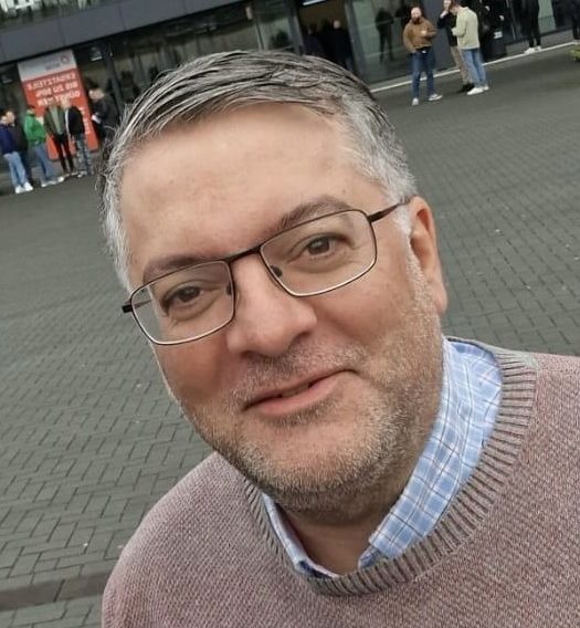 Alexandros Kotzias, Gründer von 24hydraulik Mann mit Brille und grauen Haaren, trägt einen braunen Pullover, lächelt freundlich.